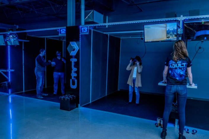 gaming-business-owner Customers engaging in a virtual reality experiences at a modern VR gaming station with interactive equipment and dynamic lighting.