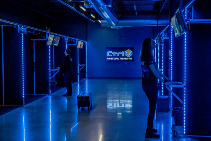 running-a-virtual-reality-business Interactive gaming experiences at Ctrl V Virtual Reality arcade, illuminated by futuristic blue neon lights, with gaming stations
